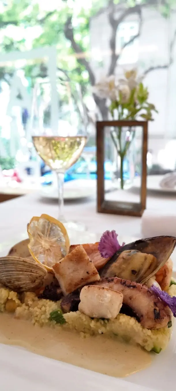 Mesa montada con un plato fuerte y copa de vino blanco