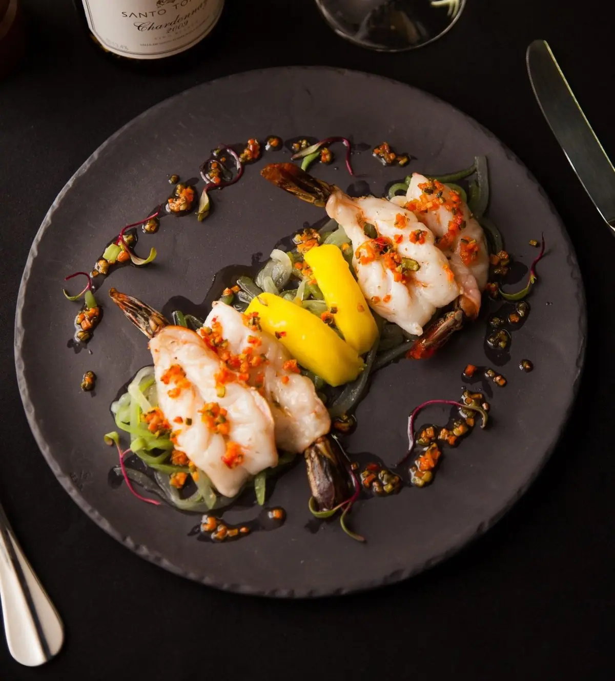 Camarones con mango y pepino sobre plato oscuro